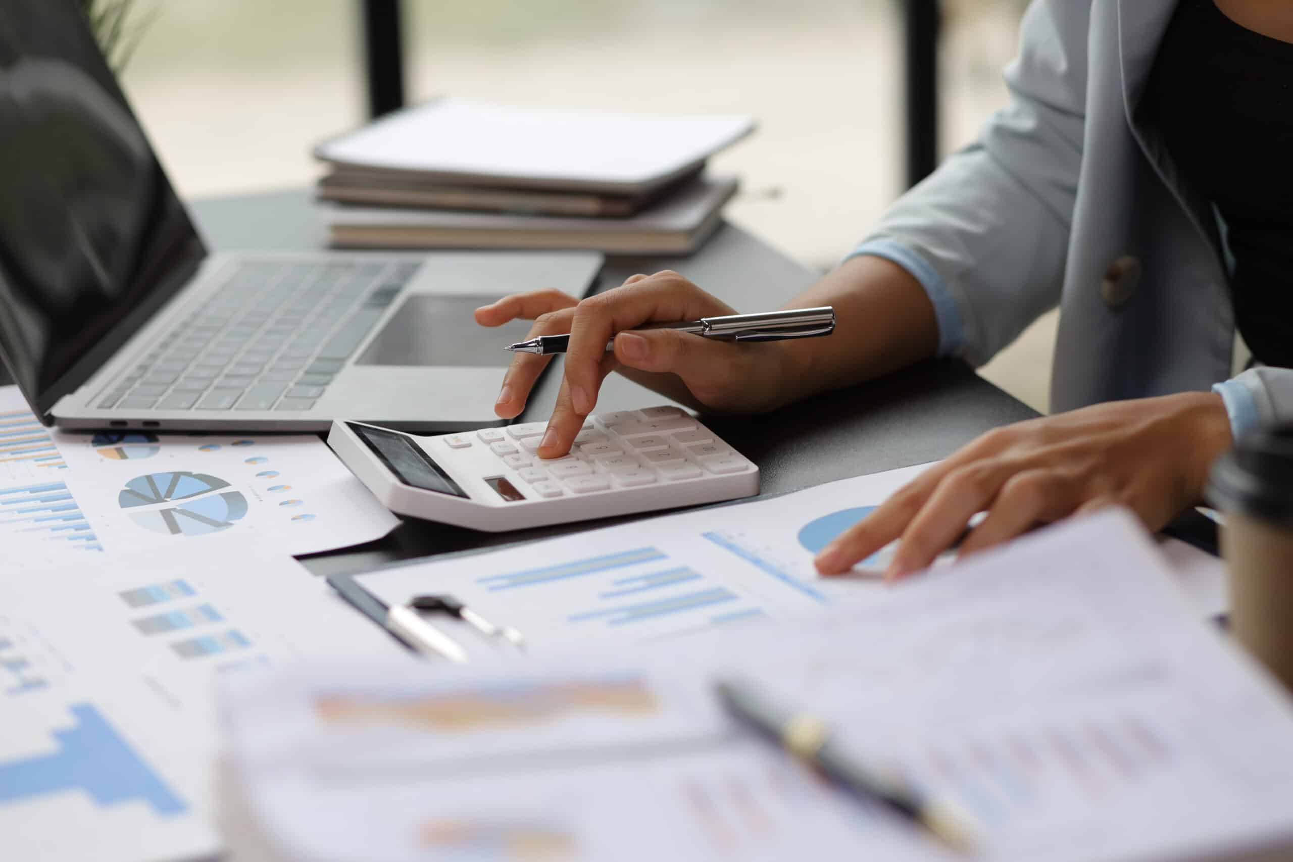 Woman sat in office with pen, calculator and financial documents.