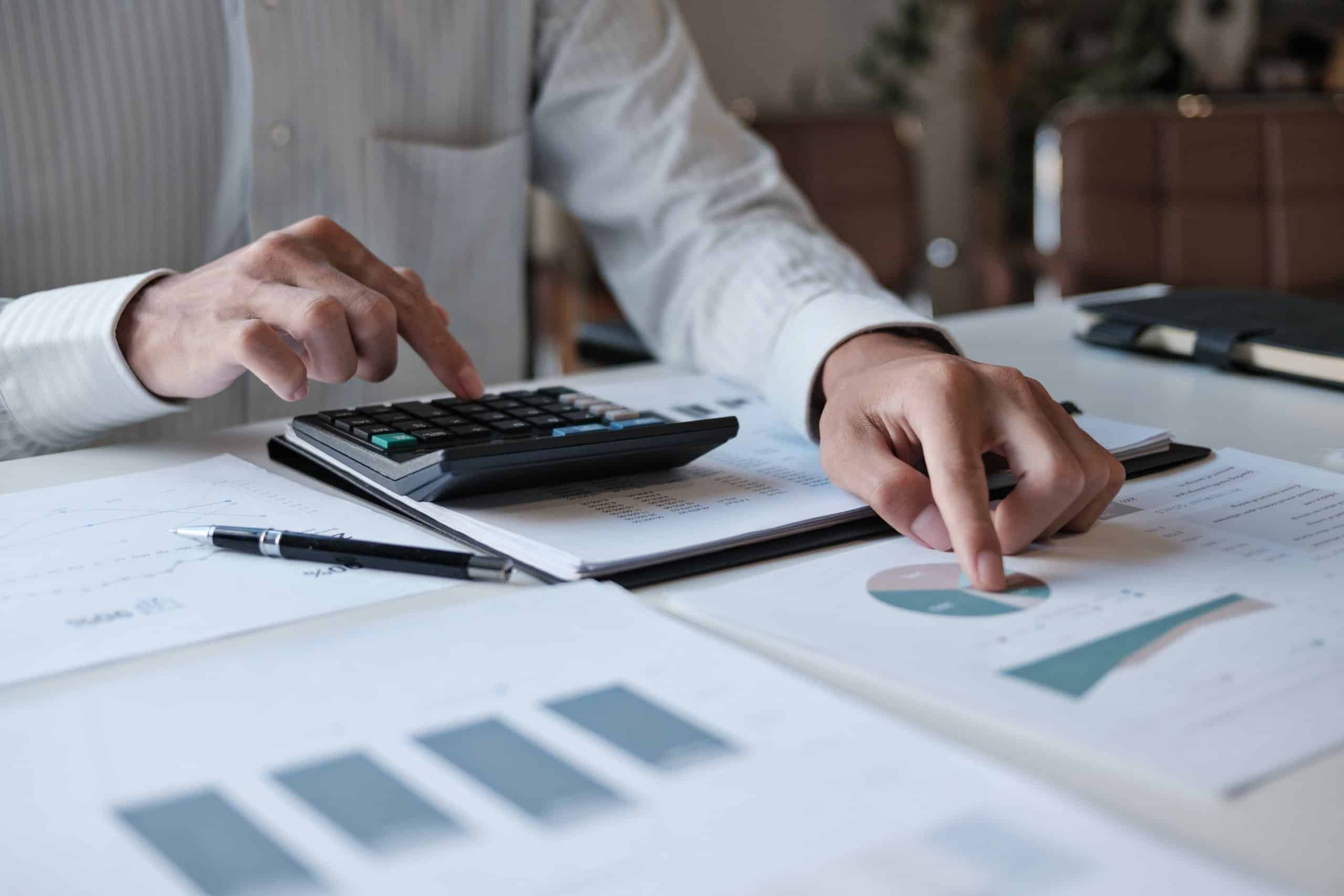 Accountant's hands on a calculator and papers, focused on financial calculations