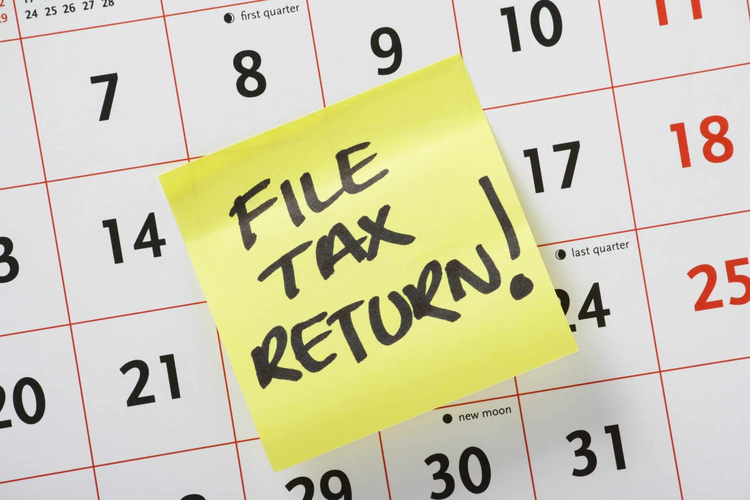 A calendar page with a yellow post-it note reading "File tax return!" prominently displayed.
